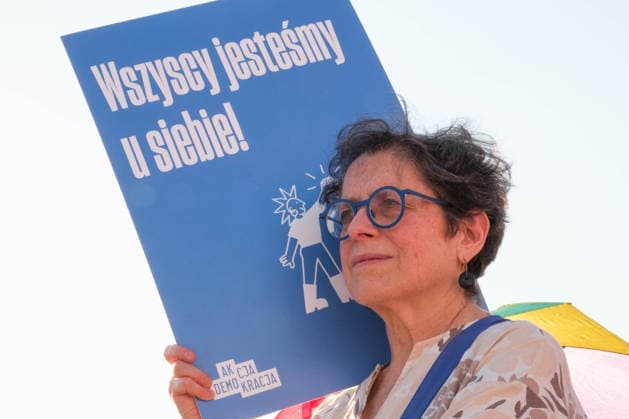 June 20, 2026, Warsaw, Masovian Voivodeship, Poland: A protester holds up a placard that reads we are all at home here! during a demonstration on Warsaw s Castle Square for World Refugee Day. Organized under the slogan open republic, the rally was held in protest against growing xenophobia towards migrants and refugees in Poland, as well as the increasing use of anti-migrant rhetoric by Polish conservatives and far-right politicians. Warsaw Poland - ZUMAk204 20260620_zip_k204_034 Copyright: xRomanxKozielx