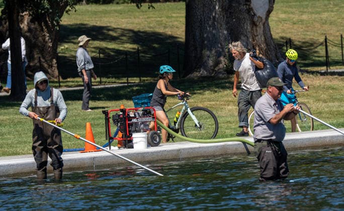 National Park Service workers use vacuum pumps to clean algae off the bottom of the newly renovated Lincoln Memorial Reflecting Pool on the National Mall in Washington, DC on Saturday, June 20,2026. The Trump Administration awarded no-bid contracts totaling nearly $15 million to renovated Reflecting Pool but it is now filled with algae and the paint is peeling. Dozens of National Guard and other police stop people from taking the blue paint chips floating in the water, with some arrests.  WAP2026062002 PATxBENIC