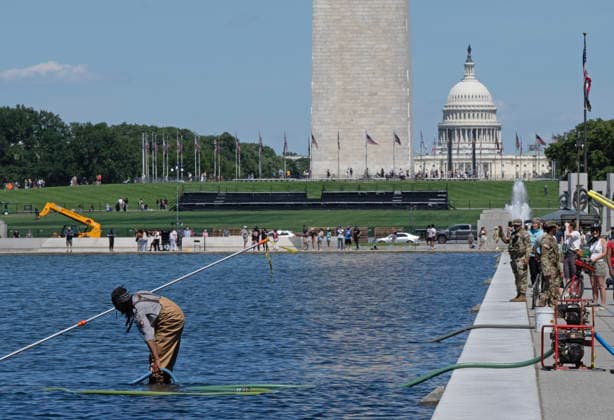 National Park Service workers use vacuum pumps to clean algae off the bottom of the newly renovated Lincoln Memorial Reflecting Pool on the National Mall in Washington, DC on Saturday, June 20,2026. The Trump Administration awarded no-bid contracts totaling nearly $15 million to renovated Reflecting Pool but it is now filled with algae and the paint is peeling. Dozens of National Guard and other police stop people from taking the blue paint chips floating in the water, with some arrests.  WAP2026062004 PATxBENIC