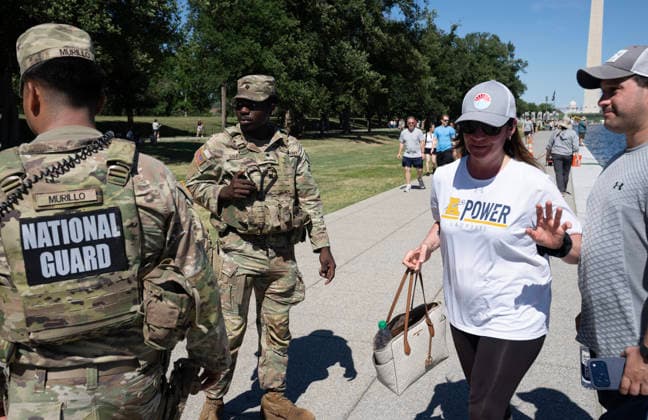 National Guard troops question a woman who fished a small blue paint chip from the newly renovated Lincoln Memorial Reflecting Pool on the National Mall in Washington, DC on Saturday, June 20,2026. She put the chip back in the water. The Trump Administration awarded no-bid contracts totaling nearly $15 million to renovated Reflecting Pool but it is now filled with algae and the paint is peeling. Dozens of National Guard and other police stop people from taking the blue paint chips floating in the water, with some arrests.  WAP2026062020 PATxBENIC