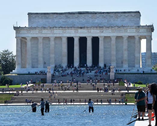 National Park Service workers use vacuum pumps to clean algae off the bottom of the newly renovated Lincoln Memorial Reflecting Pool on the National Mall in Washington, DC on Saturday, June 20,2026. The Trump Administration awarded no-bid contracts totaling nearly $15 million to renovated Reflecting Pool but it is now filled with algae and the paint is peeling. Dozens of National Guard and other police stop people from taking the blue paint chips floating in the water, with some arrests.  WAP20260620092 PATxBENIC