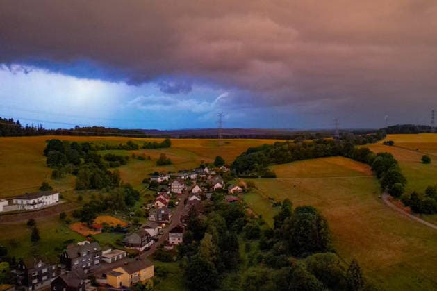 Luftaufnahme. Der Kalendarische Sommeranfang startet mit Blitz und Donner. Am fruehen (frühen) Morgen sind dunkle Wolken am Himmel wie hier ueber (über) dem Ort Siegen-Oberschelden aufgezogen. Auf der linken Seite wird der Himmel durch Blitze erhellt. Die kommenden Tage sollen sehr heiss (heiß) werden. Sommer im Siegerland am 21.06.2026 in Siegen Deutschland. *** Aerial view