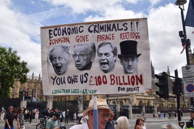 June 20, 2026, London, England, United Kingdom: A protester holds a sign calling Boris Johnson, Michael Gove, Nigel Farage and Jacob Rees-Mogg economic criminals in Parliament Square during the National Rejoin March, calling on the UK government to rejoin the European Union on the tenth anniversary of the Brexit referendum. London United Kingdom - ZUMAv130 20260620_zip_v130_075 Copyright: xVukxValcicx