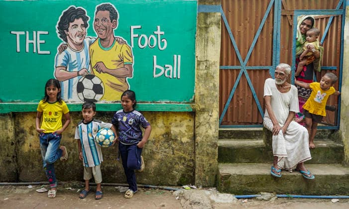 June 21, 2026, Chittagong, Chittagong, Bangladesh: Children gather around FIFA World Cup 2026-themed murals, posing with footballs, reenacting iconic celebrations and mimicking their favourite players. Painted on the walls of a residential neighbourhood, the murals have become a focal point for local youngsters, reflecting how football fever reaches beyond the pitch and brings communities together through shared passion and play. Chittagong Bangladesh - ZUMAs356 20260621_zip_s356_015 Copyright: xMohammedxSumanx