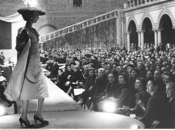 Modenschau im Blauen Saal, Stockholmer Rathaus, 1955 1955 Ein Moment der Eleganz entfaltet sich 1955 im Blauen Saal des Stockholmer Rathauses, wo ein Model die Haute Couture des Jahres präsentiert. Vor ihr sitzt ein erwartungsvolles Publikum, das sich versammelt hat, um sich die neuesten Kreationen der Haute Couture anzusehen. Die Kulisse — prachtvoll, feierlich und unverkennbar in Stockholm — verstärkt den Sinn für besondere Anlässe, während der ausgeglichene Mannekäng die raffinierten Silhouetten und die Handwerkskunst verkörpert, die die Couture der Mitte des Jahrhunderts geprägt haben. Die Szene fängt sowohl den Glamour der Modewelt als auch das kulturelle Prestige ein, sie in einem der ikonischsten Innenräume Schwedens zu präsentieren Copyright: imageBROKER Sjoberg ibljsj18096138.jpg