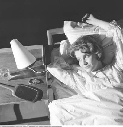 In den 1960er Jahren im Bett. Eine junge Frau liegt bequem in einem Bett. Auf dem Nachttisch stehen eine kleine Leselampe und ein Glas Wasser. Das Modell heißt Kerstin Geigert und wurde im März 1960 abgebildet In the bed in the 1960s. A young woman lies comfortably ensconced in a bed. On the bedside table is a small reading lamp and a glass of water. The models name is Kerstin Geigert pictured in march 1960 Copyright: imageBROKER Sjoberg ibljsj18096238.jpg