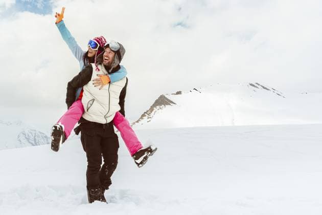 Millenniales glückliches erwachsenes Skifahrerpaar zusammen Huckepackarme hoch, gemeinsam spazieren gehen und die Freiheit des verschneiten Tages im Skigebiet der Winterberge genießen. Winterferien, Urlaub, weiße Weihnachten, Freiheit im Freien Millennial happy adult skier couple together piggyback arms up walk together enjoy snowy day freedom in winter mountains ski resort. Winter seasonal holidays vacation white xmas freedom outdoors Copyright: imageBROKER EvaldasxMikoliunas ibxemi18103135.jpg ,model released, Symbolfoto ,property released