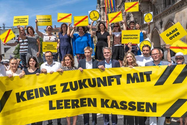 Oberbürgermeister Dominik Krause, Die Grünen, und Stadtkämmerer Christoph Frey, am Fischbrunnen beim bundesweiten Aktionstag Kommunalfinanzen, Münchner Aktion 5 vor 12, mit Mitgliedern des Stadtrats, München, 22. Juni 2026 Deutschland, München, 22. Juni 2026, Oberbürgermeister Dominik Krause, (Mitte) Die Grünen, und Stadtkämmerer Christoph Frey, (Mitte rechts), beim bundesweiten Aktionstag Kommunalfinanzen, Münchner Aktion 5 vor 12 am Fischbrunnen, Transparent: Keine Zukunft mit leeren Kassen, mit dabei: die Bürgermeisterinnen Mona Fuchs (4. von rechts) und Verena Dietl (4. von links), sowie Mitglieder des Stadtrats und der einzelnen Referate, wollen damit auf die dramatische kommunale Finanzsituation aufmerksam machen, Finanzlag