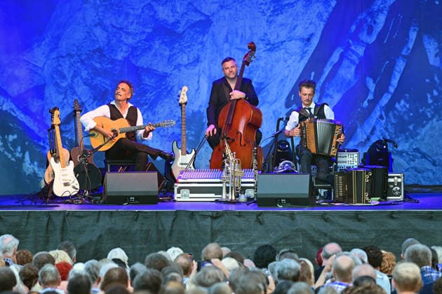 Open Air Konzert des Herbert Pixner Projekts auf der Toscana Halbinsel in Gmunden, fotografiert am 22.06.26. Das Bild zeigt v.l.n.r.: Gitarrist Manuel Rand, Bassist Werner Unterlerchner, Bandleader und Harmonikaspieler Herbert Pixner vor Publikum 2022 - Open Air Konzert des Herbert Pixner Projekts auf der Toscana HAlbinsel in Gmunden, am 22.06.26