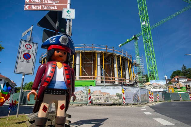 23.06.2026, Bad Wörishofen (Unterallgäu), Baustelle Löwenbräu-Arkaden Bad Wörishofen, der Neubau der Firma Glass aus Mindelheim kommt zügig voran, das Untergeschoss ist schon gut zu erkennen mit dem Rundbau und er Säulenarchitektur für die Terasse. Neben Wohnungen und Gastronomie und Tiefgaragen entsteht ein Ort der Begegnung im Herzen von Bad Wörishofen. Links eine große Playmobilfigur vom nahen Spielwarengeschäft. 23.06.2026, Bad Wörishofen 23.06.2026, Bad Wörishofen *** June 23, 2026, Bad Wörishofen, Unterallgäu; Löwenbräu Arkaden construction site in Bad Wörishofen