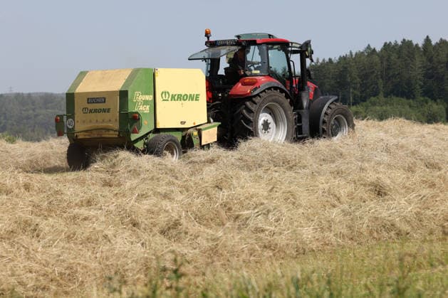 Heuernte im Siegerland. Ein Traktor mit Heuballenpresse ist bei Sonnenschein auf einer gemaehten (gemähten) Wiese bei Siegen-Oberschelden unterwegs. Sommer im Siegerland am 24.06.2026 in Siegen Deutschland. *** Hay Harvest in the Siegerland: A tractor equipped with a hay baler is driving across a mowed meadow near Siegen and Oberschelden on a sunny day. Summer in the Siegerland on June 24, 2026, in Siegen, Germany