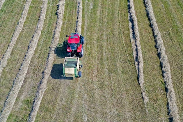 Luftaufnahme. Heuernte im Siegerland. Ein Traktor mit Heuballenpresse ist bei Sonnenschein auf einer gemaehten (gemähten) Wiese bei Siegen-Oberschelden unterwegs. Sommer im Siegerland am 24.06.2026 in Siegen Deutschland. *** Aerial view of hay harvest in the Siegerland region. A tractor equipped with a hay baler is driving across a mowed meadow near Siegen and Oberschelden on a sunny day. Summer in the Siegerland region on June 24, 2026, in Siegen, Germany.