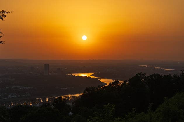 Sonnenuntergang in der Bonn Blick vom Petersberg im Siebengebirge auf Bonn bei Sonnenuntergang: Post Tower und die Hochhäuser des UN-Campus ragen aus dem goldenen Hitze-Dunst. Der Rhein mit einem Frachtschiff spiegelt das warme Abendlicht. Sommerhitze mit bis zu 35 Grad. Königswinter Petersberg Nordrhein-Westfalen Deutschland *** Sunset in Bonn: View of Bonn from Petersberg in the Siebengebirge at sunset; the Post Tower and the skyscrapers of the UN Campus rise above the golden haze of the heat; the Rhine, with a cargo ship, reflects the warm evening light; summer heat reaching up to 35 degrees; Königswinter, Petersberg, North Rhine-Westphalia Germany Copyright: xMarcxJohnx