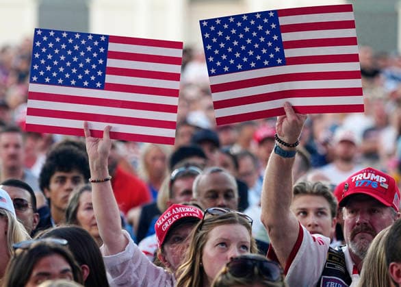 Attendees hold American flags before President Donald Trump speaks at a rally to kick off the 16-day Great American State Fair as part of Washington, D.C. s celebration of the nation s 250th birthday on the National Mall on Wednesday, June 24, 2026. The rally will include military flyovers, musical performances from Lee Greenwood and Christopher Macchio, and the U.S. Army Band, the U.S. Marine Band and Armed Forces choirs.  WAP20260624370 BONNIExCASH