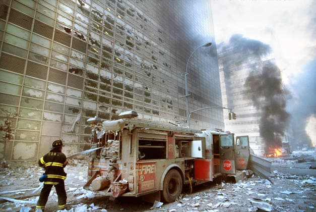September 11, 2001, New York City, New York, USA: New York City fire fighter pulling water hose from fire truck amid debris and burning buildings following September 11th terrorist attack on World Trade Center, New York City, New York, USA, Unidentified Artist New York City USA  - ZUMAg145 20010911_zap_g145_003 Copyright: xJTxVintagex