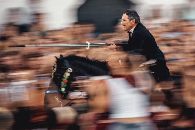 June 24, 2026, Ciutadella, Menorca Balearic Islands, Spain: A caixer (horseman) aims his spear at a suspended ring as he gallops through the cheering crowd during the Jocs des Pla (medieval tournament) during the traditional Sant Joan Ciutadella Spain - ZUMAo105 20260624_fap_o105_037 Copyright: xMatthiasxOesterlex