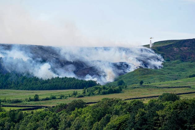June 25, 2026, Glossop, Derbyshire, UK: Glossop, UK. A helicopter throws water above a wildfire as burns near a forest in Glossop near Wood Head Reservoir, Derbyshire. A four-day amber heat and extreme heat warning has been put in place by the Met Office, with temperatures expected to peak by the end of the week. Glossop UK  - ZUMAl94_ 20260625_zaf_l94_043 Copyright: xIoannisxAlexopoulosx