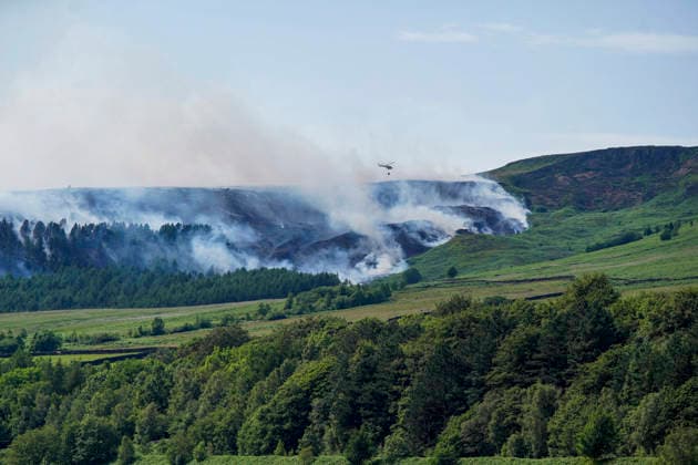 June 25, 2026, Glossop, Derbyshire, UK: Glossop, UK. A helicopter flies above a wildfire as burns near a forest in Glossop near Wood Head Reservoir, Derbyshire. A four-day amber heat and extreme heat warning has been put in place by the Met Office, with temperatures expected to peak by the end of the week. Glossop UK  - ZUMAl94_ 20260625_zaf_l94_044 Copyright: xIoannisxAlexopoulosx