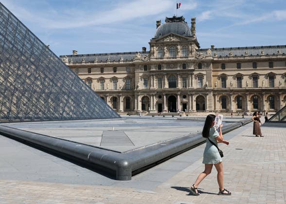 (260625) -- PARIS, June 25, 2026 -- A woman holding a folding fan is seen near the Louvre Museum amid the heatwave, in Paris, France, June 25, 2026. ) FRANCE-PARIS-HEATWAVE WuxHuiwo 