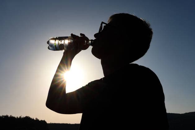 Sommer im Siegerland. Es ist sehr heiss (heiß) und die Temperaturen sollen weiter ansteigen. Der Himmel ist blau und die Sonne strahlt vom wolkenlosen Himmel. Im Vordergrund trinkt eine Frau am Morgen Wasser aus einer Flasche. Sommer am 26.06.2026 in Siegen Deutschland. *** Summer in the Siegerland. It is very hot, and temperatures are expected to rise further. The sky is blue, and the sun is shining from a cloudless sky. In the foreground, a woman is drinking water from a bottle in the morning. Summer on June 26, 2026, in Siegen, Germany.