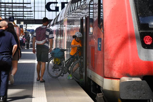 Themenfoto DB, Deutsche Bahn. Frau steigt mit Fahhrad in einen Regio Zug. Bahnreisende im Hauptbahnhof Muenchen,DB,Die Bahn, Fernverkehr,Hauptbahnhof Muenchen, Regiozug,Regionalverkehr,Lokomotive.