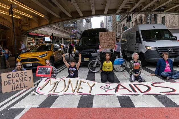 June 26, 2026, New York, New York, USA: Members of ACT UP New York begin Pride weekend with an act of civil disobedience blockading traffic during the morning rush hour on 42nd Street outside Grand Central Station stating solidarity with striking Delaney Hall immigrant detainees and denouncing Trump administration cuts to AIDS funding and healthcare. After traffic is at a standstill for approximately 40 minutes, NYPD arrests demonstrators. The protest banner is Ã¢â‚¬ËœMoney for AIDS and Healthcare Not for ICE and Warfare. Protesters hold signs that reads CLOSE DELANEY HALL. Demonstrators defend New YorkÃ¢â‚¬â ¢s sanctuary city status as an ICE surge is promised and protest funding cuts to AIDS Drug Assistance Programs (ADAP,) The U.S. Pr  - ZUMAr174 20260626_znp_r174_020 Copyright: xGinaxMxRandazzox