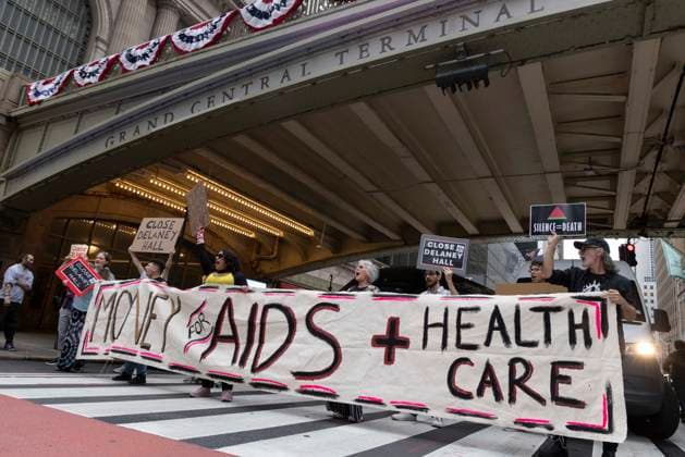 June 26, 2026, New York, New York, USA: Members of ACT UP New York begin Pride weekend with an act of civil disobedience blockading traffic during the morning rush hour on 42nd Street outside Grand Central Station stating solidarity with striking Delaney Hall immigrant detainees and denouncing Trump administration cuts to AIDS funding and healthcare. After traffic is at a standstill for approximately 40 minutes, NYPD arrests demonstrators. The protest banner is Ã¢â‚¬ËœMoney for AIDS and Healthcare Not for ICE and Warfare. Protesters hold signs that read SILENCE equals DEATH CLOSE DELANEY HALL. Demonstrators defend New YorkÃ¢â‚¬â ¢s sanctuary city status as an ICE surge is promised and protest funding cuts to AIDS Drug Assistance Progra - ZUMAr174 20260626_znp_r174_014 Copyright: xGinaxMxRandazzox