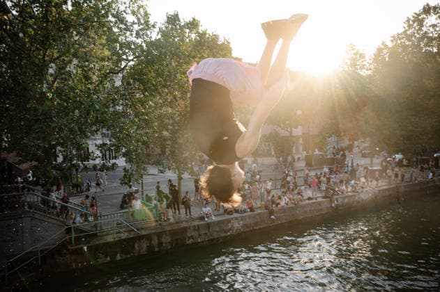 Parisians Swim In The Canal Saint-Martin To Escape The Heatwave A man performs an acrobatic move mid-jump over the Canal Saint-Martin, with the setting sun in the background, in Paris, France, on June 26, 2026. Parisians swim to cool off during the intense heatwave that has placed the capital under a red alert. Paris France  Copyright: xSamuelxBoivinx originalFilename: boivin-notitle260626_np7x6.jpg