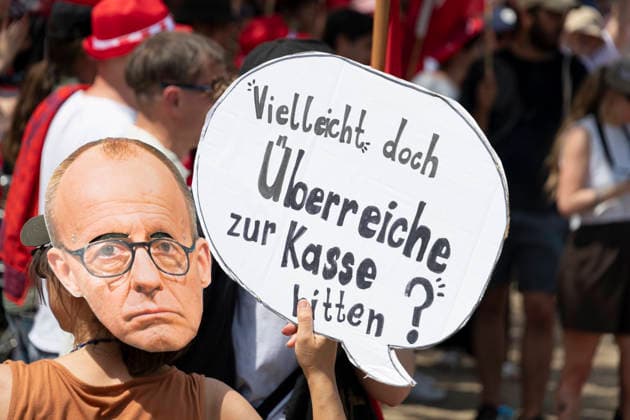 Protest gegen Sozialstaatsreform EUR, Deutschland, Berlin, 27.06.2026: Frau mit einem Foto von Friedrich Merz am Hinterkopf und einer Sprechblase Vielleicht doch Überreiche zur Kasse bitten? . Ein breites Bündnis aus Gewerkschaften, Sozial- und Wohlfahrtsverbänden sowie der Berliner Mieterverein protestieren gegen die geplanten Sozialstaatsreformen der Bundesregierung *** Protest Against Welfare State Reform, EUR, Germany, Berlin, June 27, 2026 Woman with a photo of Friedrich Merz on the back of her head and a speech bubble: Maybe we should make the super-rich pay after all. A broad coalition of labor unions, social and welfare organizations, and the Berlin Tenants’ Association is protesting the federal government’s planned welfare s