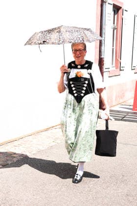 27.06.2026 Basel Schweiz.Hitzewelle Hitze Eidgenoessisches Jodlerfest Basel Bild ,Jdlerin in Tracht schuetzt sich mit Schirm vor der Sonne. *** June 27, 2026, Basel, Switzerland: Heat wave, heat, Swiss Yodeling Festival in Basel. Photo: A female yodeler in traditional costume shields herself from the sun with an umbrella. 