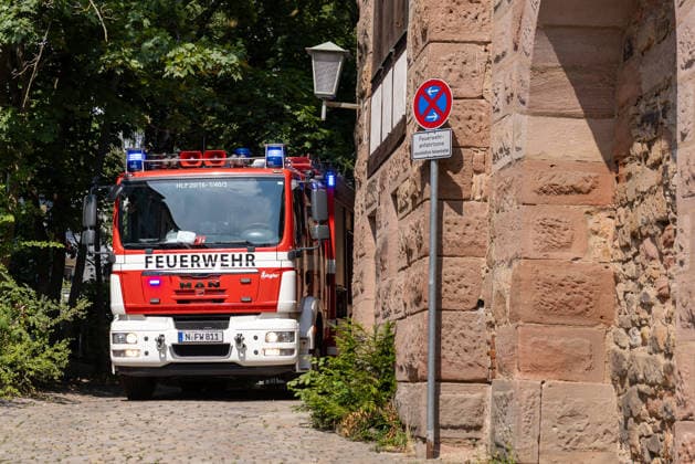 Wohnungsbrand in Mehrfamilienhaus in der Sebalder Altstadt - Spitzberg, Nürnberg, 28.06.2026 Ein Hilfeleistungsfahrzeug HLF 20 der Feuerwehr Nürnberg steht in einer engen Gasse direkt an der Stadtmauer, unmittelbar neben einem Schild Feuerwehranfahrtszone . Bei Sommerhitze von rund 36Â°C laufen Löscharbeiten nach einem Brand in einem Mehrfamilienhaus in der Sebalder Altstadt. *** Apartment Fire in an Apartment Building in the Sebalder Altstadt Spitzberg, Nuremberg, June 28, 2026 A HLF 20 rescue vehicle from the Nuremberg Fire Department is parked in a narrow alley right next to the city wall, right next to a sign reading Fire Department Access Zone. With summer temperatures around 36°C, firefighting operations are underway follo 20260628-286A0514-M4000