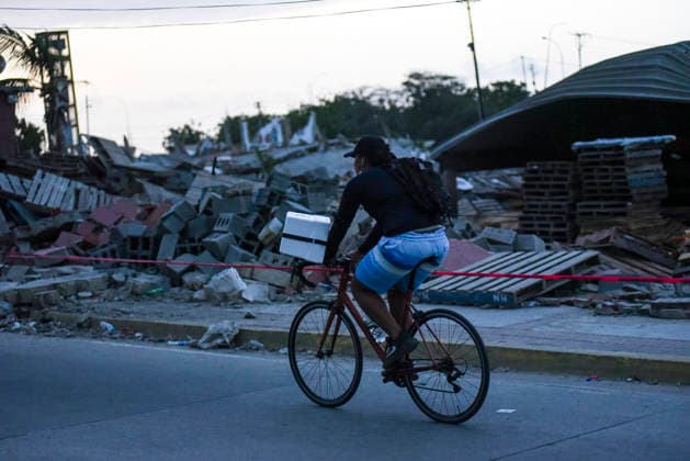 A man rides a bicycle past destroyed buildings as rescue teams continue searching for victims amid debris of a demolished building after a magnitude 7.2 earthquake struck Venezuela and other regions in the Caribbean in La Guaira, Venezuela, on June 27, 2026. According to the U.S. Geological Survey, a powerful 7.5?magnitude aftershock struck after the main quake. Medical and media sources reported that the death toll has risen to around 1,500, with some 3,000 others injured. A web page created to track the missing has listed nearly 50,000 people as unaccounted for.  VAN2026062826 JonathanxLanza