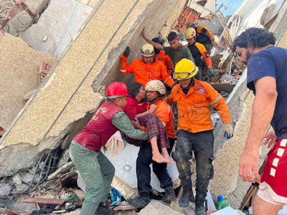 Rescue teams carry an injured survivor while continuing the search for those trapped beneath the rubble of collapsed residential buildings in affected areas following the powerful 7.2‘magnitude earthquake that struck Venezuela and parts of the Caribbean on June 29, 2026. The death toll has risen to over 1,400, with more than 3,000 injured, while authorities report that over 70,000 people remain missing.  VAN2026062903 GovernmentxMinistryxofxInformati