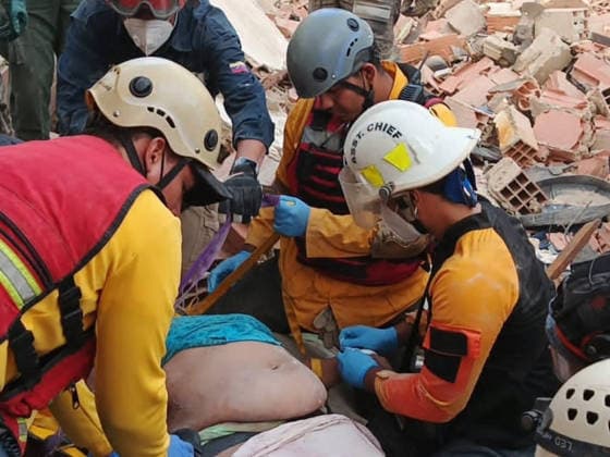 Rescue teams carry an injured survivor while continuing the search for those trapped beneath the rubble of collapsed residential buildings in affected areas following the powerful 7.2‘magnitude earthquake that struck Venezuela and parts of the Caribbean on June 29, 2026. The death toll has risen to over 1,400, with more than 3,000 injured, while authorities report that over 70,000 people remain missing.  VAN2026062905 GovernmentxMinistryxofxInformati