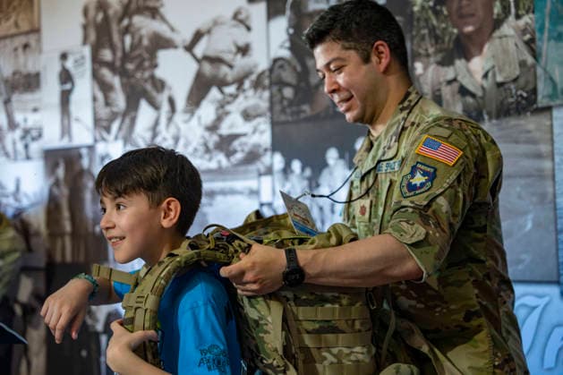 Kids put on weighted army tactical backpacks in the Department of War exhibit during the fifth day of the Great American State Fair on the National Mall on Monday, June 29, 2026. The Freedom 250-backed Great American State Fair celebrating the 250th anniversary of the United States runs through July 10th.  WAP20260629405 BONNIExCASH