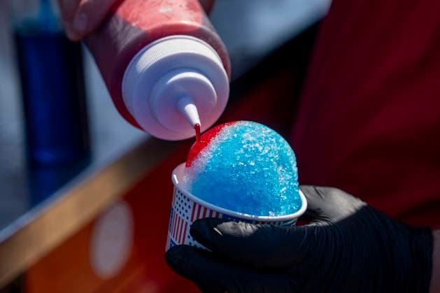An employee adds syrup to a snow cone during the fifth day of the Great American State Fair on the National Mall on Monday, June 29, 2026. The Freedom 250-backed Great American State Fair celebrating the 250th anniversary of the United States runs through July 10th.  WAP20260629413 BONNIExCASH