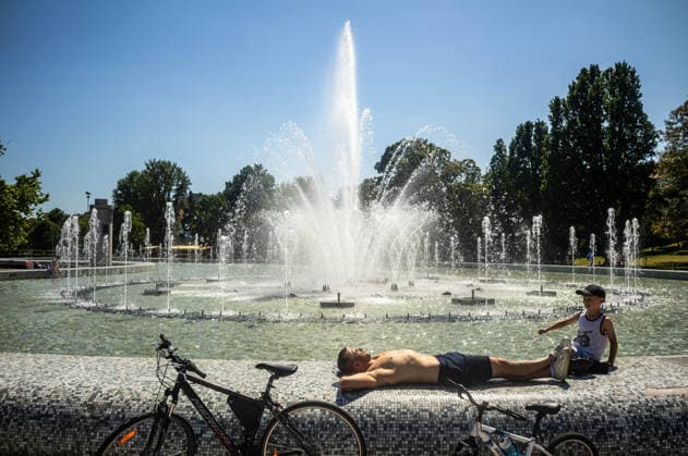June 27, 2026, Warsaw, Mazovia, Poland: A father and son relax in the sun next to a fountain. On the afternoon of the 28th of June, Varsovians cool and hydrate themselves around the city during a record-breaking heatwave. Due to the extreme heat, the authorities provided misting sprays and water tanks around the city. During the weekend, Warsaw experienced temperatures approaching 38Â°C as the unprecedented European heatwave swept across Poland, roughly 15Â°C above the late-June average. Tropical nights, nationwide heat alerts, and temperatures up to 40.5Â°C elsewhere in the country made this one of the most extreme heat events in modern Polish history. Warsaw Poland - ZUMAs197 20260627_aaa_s197_324 Copyright: xNeilxMiltonx