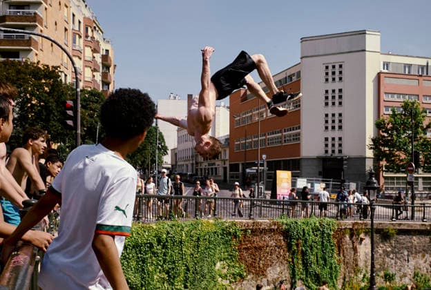 Heatwave Canal Saint Martin Paris People watch as a youth performs a backflip into the Canal Saint-Martin in Paris, France, on June 23, 2026. As France experiences a major heatwave, people use the Canal Saint-Martin as an improvised urban beach to cool off. While the city recently opened a regulated swimming area, the extreme temperatures have led many to swim in unapproved sections of the waterway. Paris Ile de France France Copyright: xOliviaxBonnamourx