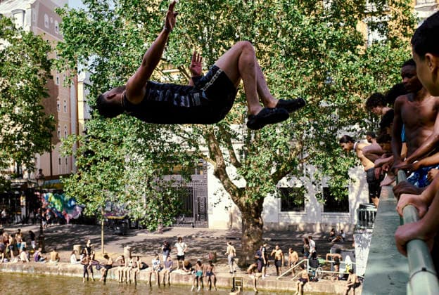 Heatwave Canal Saint Martin Paris People watch as a man performs a backflip from a footbridge into the Canal Saint-Martin in Paris, France, on June 23, 2026. As France experiences a major heatwave, people use the Canal Saint-Martin as an improvised urban beach to cool off. While the city recently opened a regulated swimming area, the extreme temperatures have led many to swim in unapproved sections of the waterway. Paris Ile de France France Copyright: xOliviaxBonnamourx