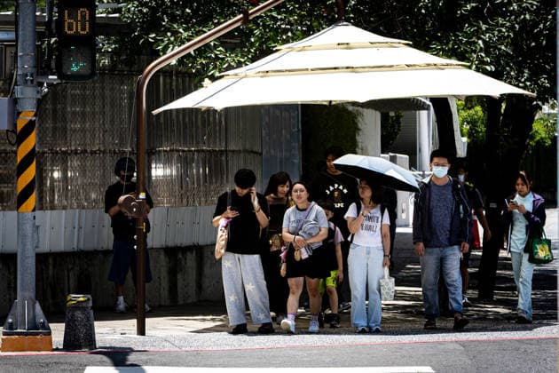 July 1, 2026, Kaohsiung City, Kaohsiung City, Taiwan: Transit commuters cross a crosswalk near a manual street parasol, set up by the city to provide temporary shade during hot summer days in Kaohsiung, Taiwan, on July 1, 2026 Kaohsiung City Taiwan - ZUMAh198 20260701_zip_h198_002 Copyright: xCheng-ChiaxHuangx
