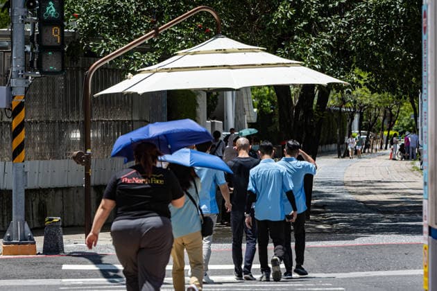 July 1, 2026, Kaohsiung City, Kaohsiung City, Taiwan: PedestTurning a busy transit intersection in Kaohsiung into a brief respite, a giant manual sunshade umbrella casts a wide shadow for pedestrians crossing the pavement on July 1, 2026 Kaohsiung City Taiwan - ZUMAh198 20260701_zip_h198_004 Copyright: xCheng-ChiaxHuangx