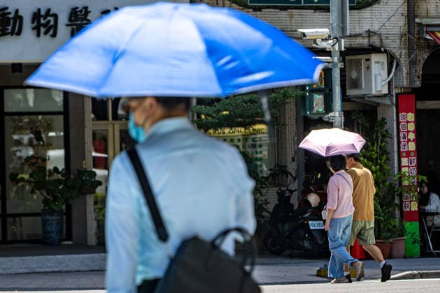 July 1, 2026, Kaohsiung City, Kaohsiung City, Taiwan: A pedestrian with a large blue umbrella walks past a street corner in Kaohsiung where manual public sunshades have been deployed to improve pedestrian comfort during extreme heat on July 1, 2026 Kaohsiung City Taiwan - ZUMAh198 20260701_zip_h198_008 Copyright: xCheng-ChiaxHuangx