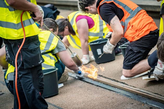 Leipziger Bürgerinnen und Bürger befreien am Johannisplatz gemeinsam mit den Leipziger Verkehrsbetrieben (LVB) die Straßenbahngleise von geschmolzenem Bitumen. Nachdem bereits am Vortag rund 100 Freiwillige einem Aufruf der LVB gefolgt waren, wurden die Reinigungsarbeiten am zweiten Tag am Johannisplatz fortgesetzt. Hintergrund sind die Schäden durch die extremen Temperaturen des vergangenen Hitzewochenendes. Aufnahme vom Datum . Reinigung Leipzig *** Residents of Leipzig are working together with the Leipzig Public Transportation Authority (LVB) to clear melted asphalt from the tram tracks at Johannisplatz. After about 100 volunteers had already responded to a call for help from the LVB the previous day, cleanup efforts continued on t