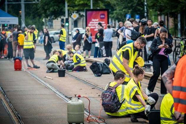 Leipziger Bürgerinnen und Bürger befreien am Johannisplatz gemeinsam mit den Leipziger Verkehrsbetrieben (LVB) die Straßenbahngleise von geschmolzenem Bitumen. Nachdem bereits am Vortag rund 100 Freiwillige einem Aufruf der LVB gefolgt waren, wurden die Reinigungsarbeiten am zweiten Tag am Johannisplatz fortgesetzt. Hintergrund sind die Schäden durch die extremen Temperaturen des vergangenen Hitzewochenendes. Aufnahme vom Datum . Reinigung Leipzig *** Residents of Leipzig are working together with the Leipzig Public Transportation Authority (LVB) to clear melted asphalt from the tram tracks at Johannisplatz. After about 100 volunteers had already responded to a call for help from the LVB the previous day, cleanup efforts continued on t