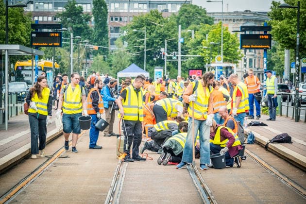 Leipziger Bürgerinnen und Bürger befreien am Johannisplatz gemeinsam mit den Leipziger Verkehrsbetrieben (LVB) die Straßenbahngleise von geschmolzenem Bitumen. Nachdem bereits am Vortag rund 100 Freiwillige einem Aufruf der LVB gefolgt waren, wurden die Reinigungsarbeiten am zweiten Tag am Johannisplatz fortgesetzt. Hintergrund sind die Schäden durch die extremen Temperaturen des vergangenen Hitzewochenendes. Aufnahme vom Datum . Reinigung Leipzig *** Residents of Leipzig are working together with the Leipzig Public Transportation Authority (LVB) to clear melted asphalt from the tram tracks at Johannisplatz. After about 100 volunteers had already responded to a call for help from the LVB the previous day, cleanup efforts continued on t