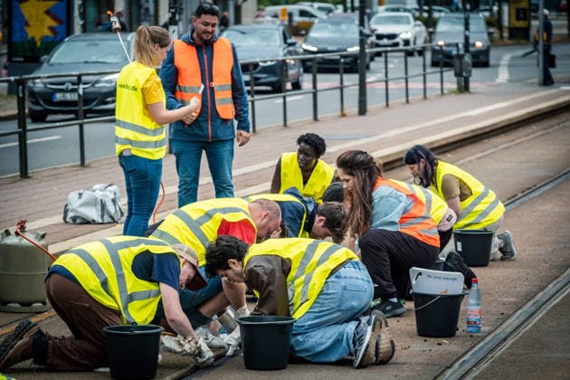 Leipziger Bürgerinnen und Bürger befreien am Johannisplatz gemeinsam mit den Leipziger Verkehrsbetrieben (LVB) die Straßenbahngleise von geschmolzenem Bitumen. Nachdem bereits am Vortag rund 100 Freiwillige einem Aufruf der LVB gefolgt waren, wurden die Reinigungsarbeiten am zweiten Tag am Johannisplatz fortgesetzt. Hintergrund sind die Schäden durch die extremen Temperaturen des vergangenen Hitzewochenendes. Aufnahme vom Datum . Reinigung Leipzig *** Residents of Leipzig are working together with the Leipzig Public Transportation Authority (LVB) to clear melted asphalt from the tram tracks at Johannisplatz. After about 100 volunteers had already responded to a call for help from the LVB the previous day, cleanup efforts continued on t