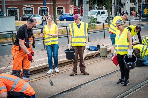 Leipziger Bürgerinnen und Bürger befreien am Johannisplatz gemeinsam mit den Leipziger Verkehrsbetrieben (LVB) die Straßenbahngleise von geschmolzenem Bitumen. Nachdem bereits am Vortag rund 100 Freiwillige einem Aufruf der LVB gefolgt waren, wurden die Reinigungsarbeiten am zweiten Tag am Johannisplatz fortgesetzt. Hintergrund sind die Schäden durch die extremen Temperaturen des vergangenen Hitzewochenendes. Aufnahme vom Datum . Reinigung Leipzig *** Residents of Leipzig are working together with the Leipzig Public Transportation Authority (LVB) to clear melted asphalt from the tram tracks at Johannisplatz. After about 100 volunteers had already responded to a call for help from the LVB the previous day, cleanup efforts continued on t