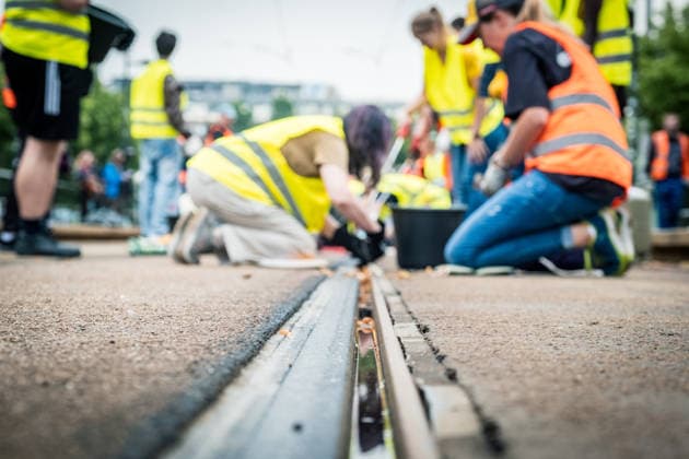 Leipziger Bürgerinnen und Bürger befreien am Johannisplatz gemeinsam mit den Leipziger Verkehrsbetrieben (LVB) die Straßenbahngleise von geschmolzenem Bitumen. Nachdem bereits am Vortag rund 100 Freiwillige einem Aufruf der LVB gefolgt waren, wurden die Reinigungsarbeiten am zweiten Tag am Johannisplatz fortgesetzt. Hintergrund sind die Schäden durch die extremen Temperaturen des vergangenen Hitzewochenendes. Aufnahme vom Datum . Reinigung Leipzig *** Residents of Leipzig are working together with the Leipzig Public Transportation Authority (LVB) to clear melted asphalt from the tram tracks at Johannisplatz. After about 100 volunteers had already responded to a call for help from the LVB the previous day, cleanup efforts continued on t