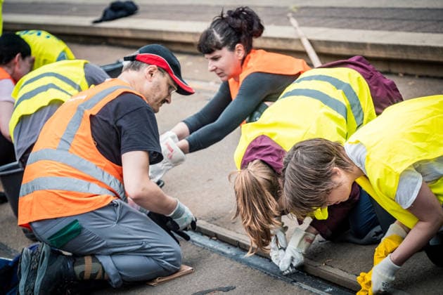 Leipziger Bürgerinnen und Bürger befreien am Johannisplatz gemeinsam mit den Leipziger Verkehrsbetrieben (LVB) die Straßenbahngleise von geschmolzenem Bitumen. Nachdem bereits am Vortag rund 100 Freiwillige einem Aufruf der LVB gefolgt waren, wurden die Reinigungsarbeiten am zweiten Tag am Johannisplatz fortgesetzt. Hintergrund sind die Schäden durch die extremen Temperaturen des vergangenen Hitzewochenendes. Aufnahme vom Datum . Reinigung Leipzig *** Residents of Leipzig are working together with the Leipzig Public Transportation Authority (LVB) to clear melted asphalt from the tram tracks at Johannisplatz. After about 100 volunteers had already responded to a call for help from the LVB the previous day, cleanup efforts continued on t