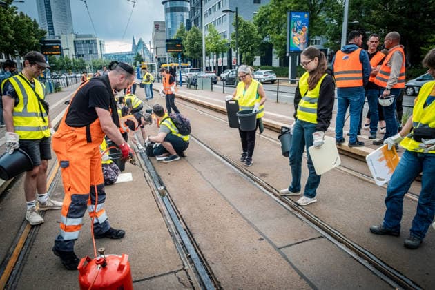 Leipziger Bürgerinnen und Bürger befreien am Johannisplatz gemeinsam mit den Leipziger Verkehrsbetrieben (LVB) die Straßenbahngleise von geschmolzenem Bitumen. Nachdem bereits am Vortag rund 100 Freiwillige einem Aufruf der LVB gefolgt waren, wurden die Reinigungsarbeiten am zweiten Tag am Johannisplatz fortgesetzt. Hintergrund sind die Schäden durch die extremen Temperaturen des vergangenen Hitzewochenendes. Aufnahme vom Datum . Reinigung Leipzig *** Residents of Leipzig are working together with the Leipzig Public Transportation Authority (LVB) to clear melted asphalt from the tram tracks at Johannisplatz. After about 100 volunteers had already responded to a call for help from the LVB the previous day, cleanup efforts continued on t